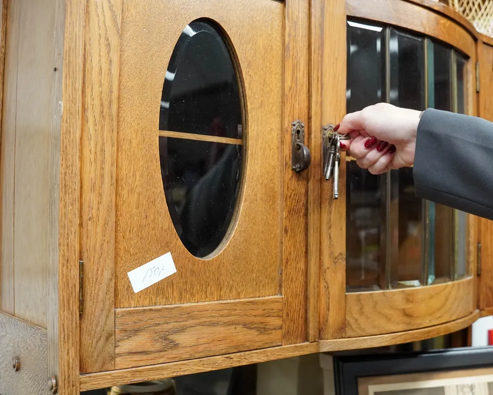 Een eikenhouten kast met ovaal glas wordt met de sleutel geopend