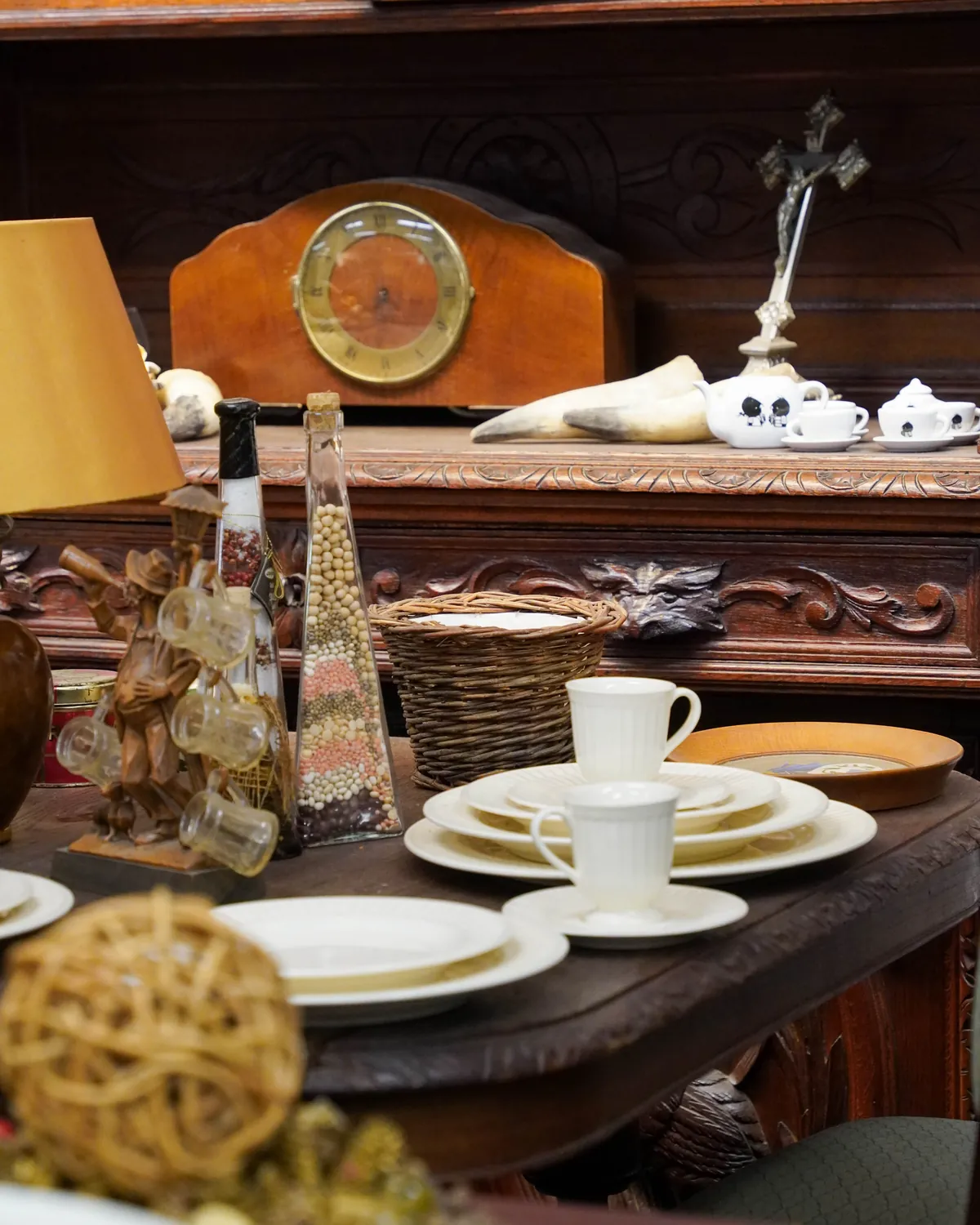 Een gedekte houten tafel met een schemerlamp en een klok