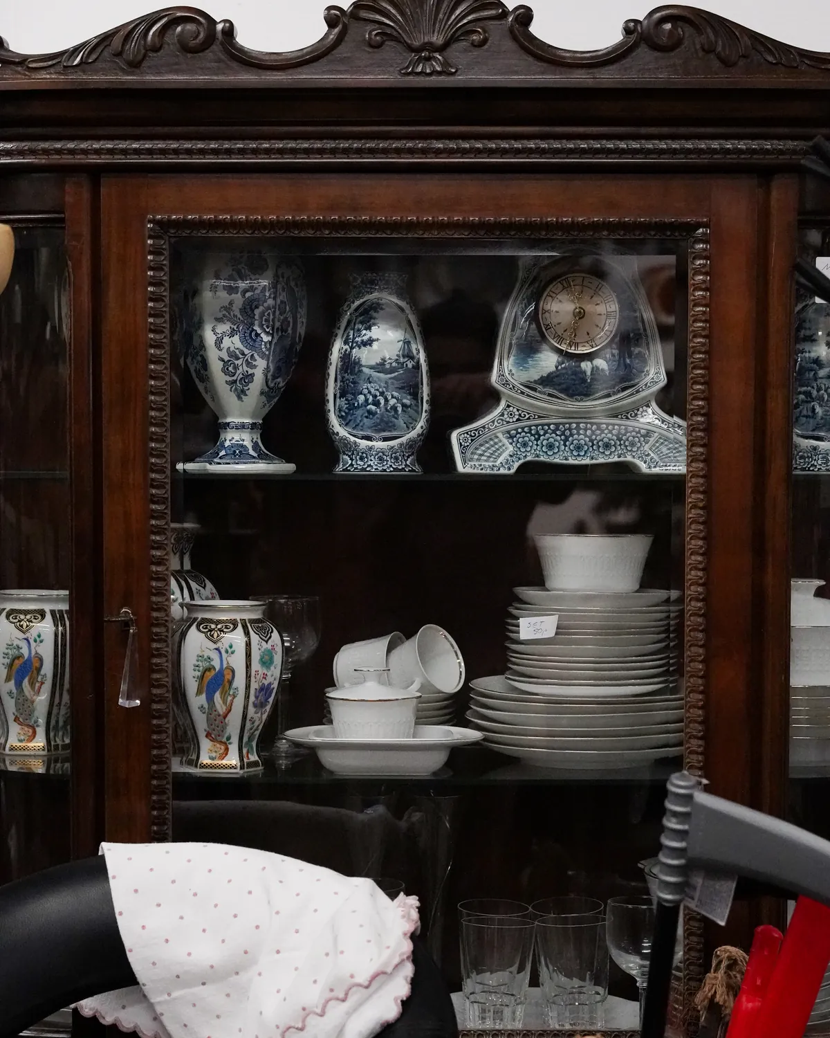Een donkere houten vitrinekast met Delfts blauwe vazen en servies